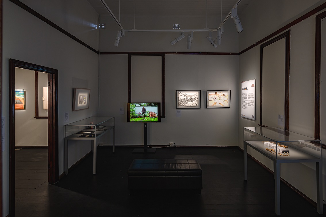 Exhibition installation view with spotlight on various artworks and display cases