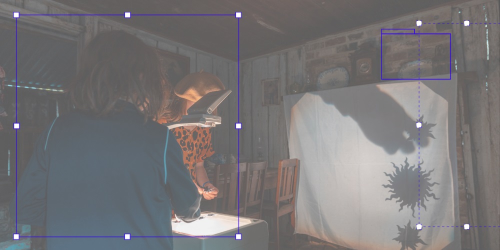 Kids placing paper cut outs on an overhead projector to make shadows on a white screen