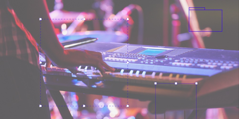 Hands play on a keyboard in purple and pink lighting 