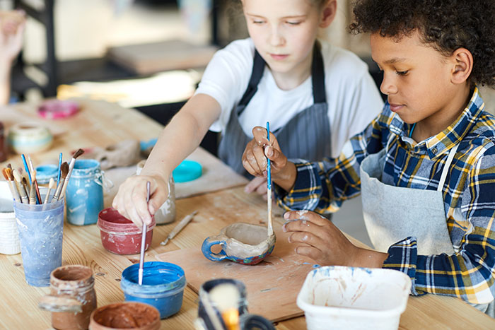 Two young children painting small ceramic cups